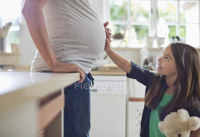 Girl holding pregnant mothers belly — Stock Photo