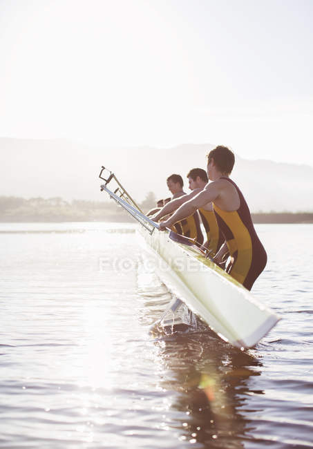 Команда гребцов опускает лодку в озеро — стоковое фото