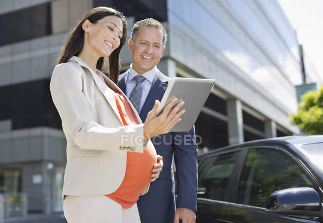 Embarazada mujer de negocios y colega utilizando tableta - foto de stock