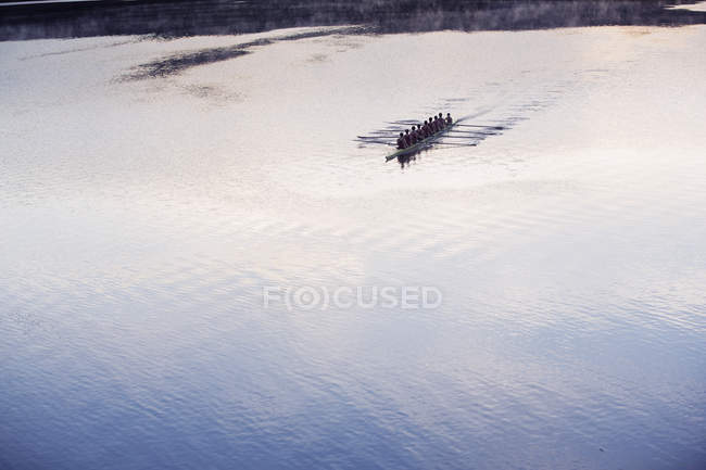 Rowing crew rowing scull on lake in distance — Stock Photo