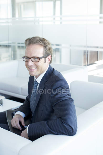Бізнесмен сидить на дивані в офісному вестибюлі — стокове фото
