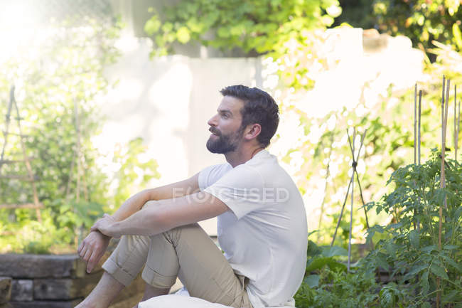 Улыбающийся мужчина расслабляется на заднем дворе — стоковое фото