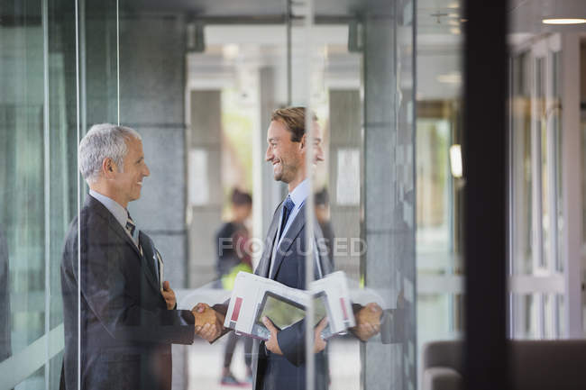 Empresários apertando as mãos no prédio de escritórios moderno — Fotografia de Stock