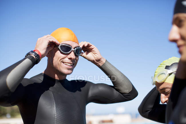 Smiling triathlete adjusting goggles outdoors — Stock Photo