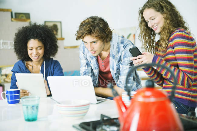 Young happy friends relaxing together in kitchen — Stock Photo