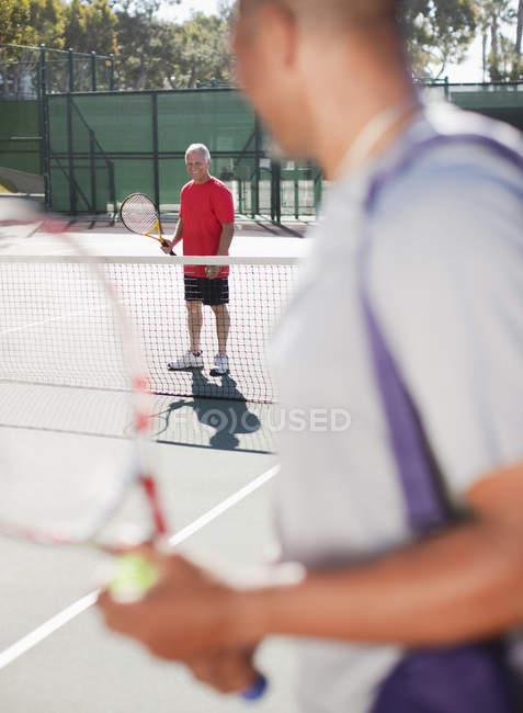 Hombres mayores jugando al tenis en la cancha - foto de stock