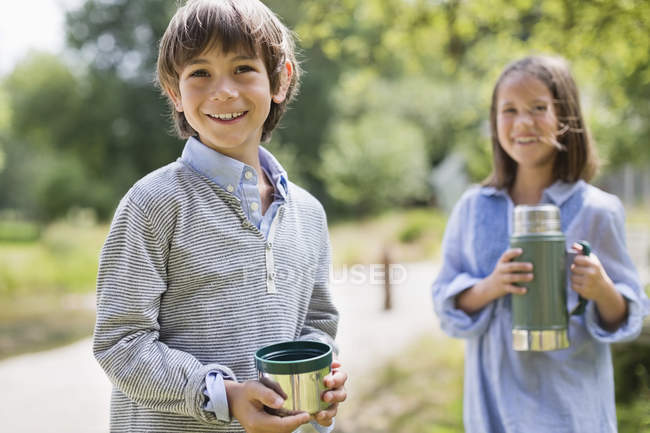 Дети пьют из термоса на открытом воздухе — стоковое фото