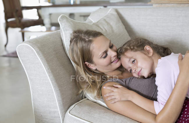 Madre e hija relajándose en el sofá - foto de stock
