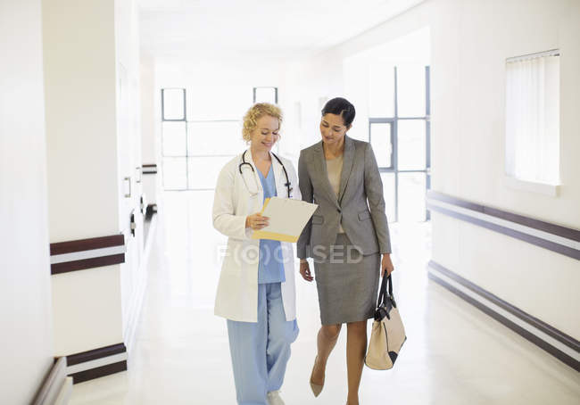 Лікар і бізнес-леді розмовляють в лікарняному коридорі — стокове фото
