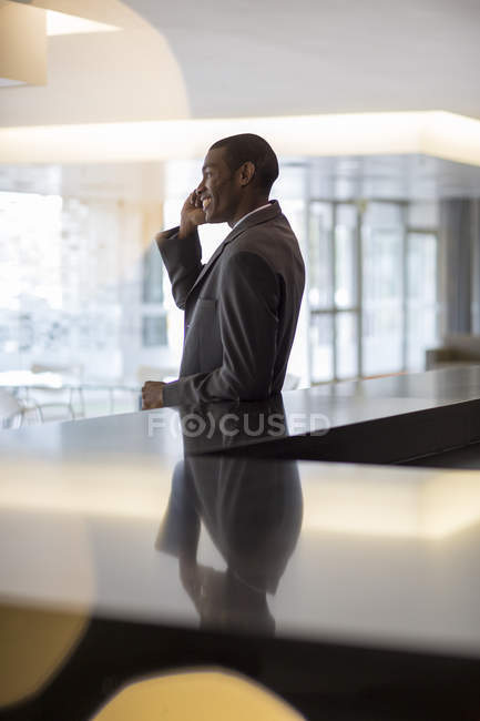 Smiling businessman talking on cell phone in lobby at modern office — Stock Photo