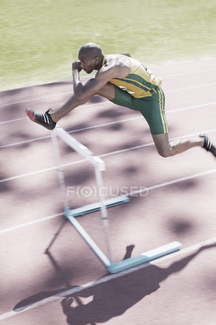 Runner clearing hurdle on track — Stock Photo