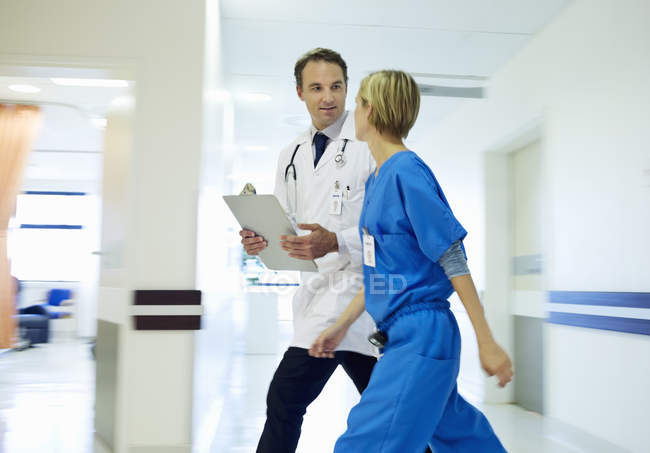 Médico y enfermera caminando en el pasillo del hospital - foto de stock