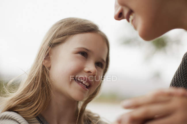 Nahaufnahme einer lächelnden Tochter, die zu ihrer Mutter aufschaut — Stockfoto