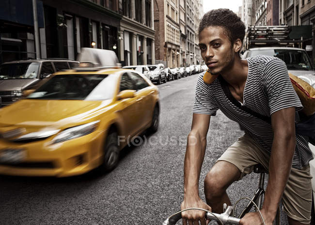 Молодой человек на велосипеде по улице города — стоковое фото