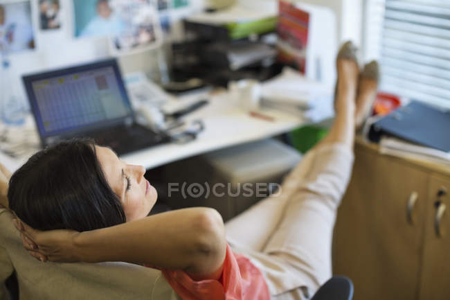 Geschäftsfrau entspannt sich am Schreibtisch im modernen Büro — Stockfoto