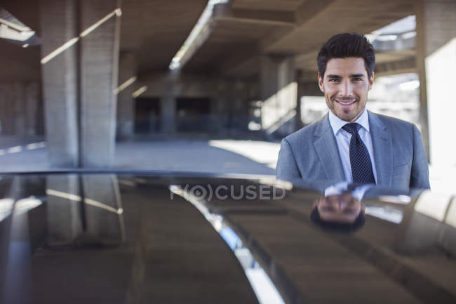 Businessman standing near car in parking garage — Stock Photo