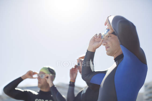 Triatletas seguros y fuertes que ajustan las gafas al aire libre - foto de stock