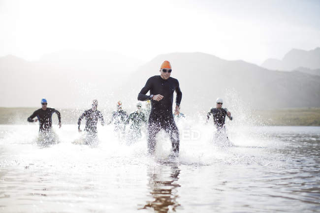 Triatletas confiantes e fortes emergindo da água — Fotografia de Stock
