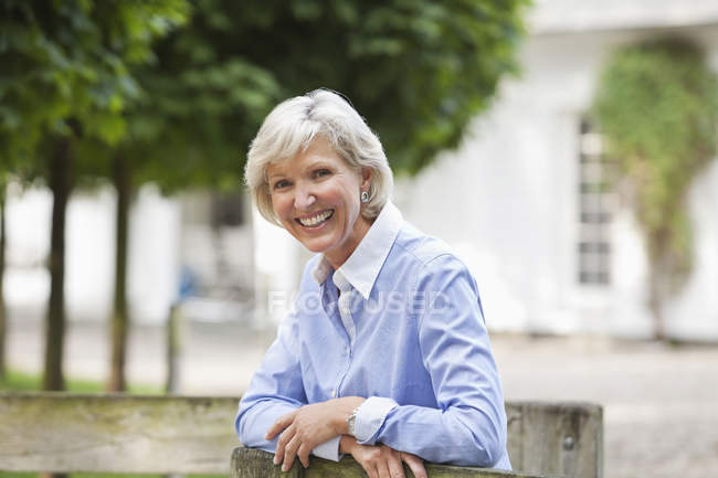 Woman leaning on wooden fence — Stock Photo