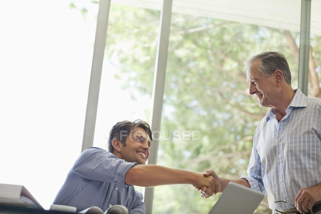 Men shaking hands in living room — Stock Photo