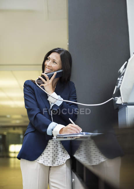 Businesswoman talking on pay phone outdoors — Stock Photo