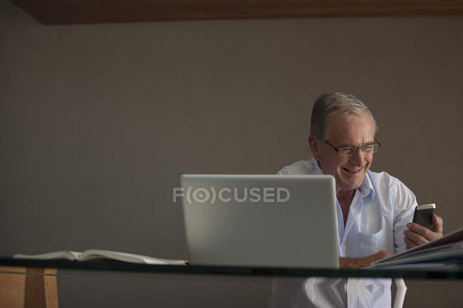 Businessman using cell phone at desk — Stock Photo