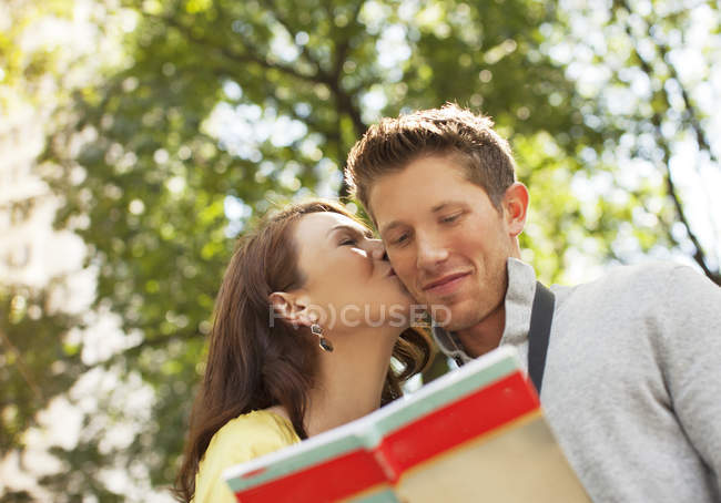 Mulher beijando namorado no parque — Fotografia de Stock