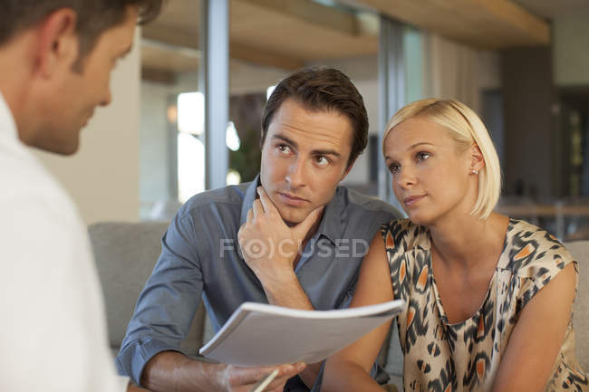 Conselheiro financeiro conversando com casal no sofá — Fotografia de Stock