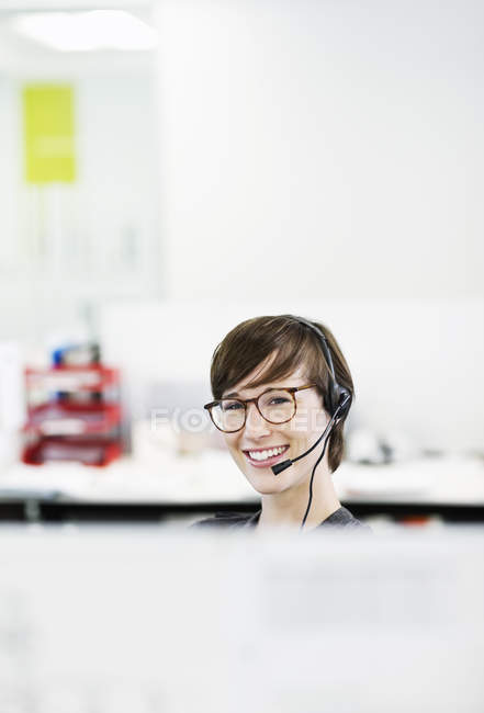 Mulher de negócios usando fone de ouvido no escritório moderno — Fotografia de Stock