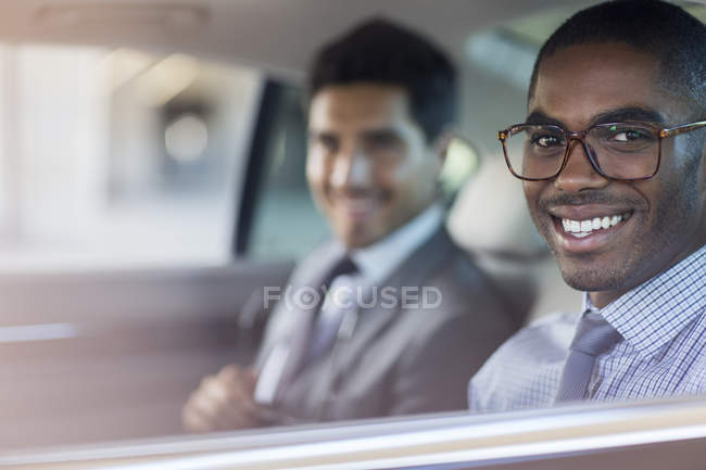 Des hommes d'affaires souriants assis dans une voiture — Photo de stock