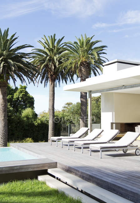Liegestühle am Pool eines modernen Hauses — Stockfoto