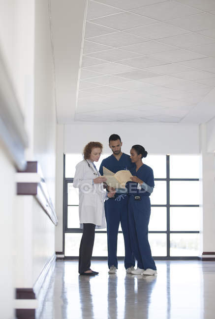 Персонал лікарні розмовляє в сучасному лікарняному коридорі — стокове фото