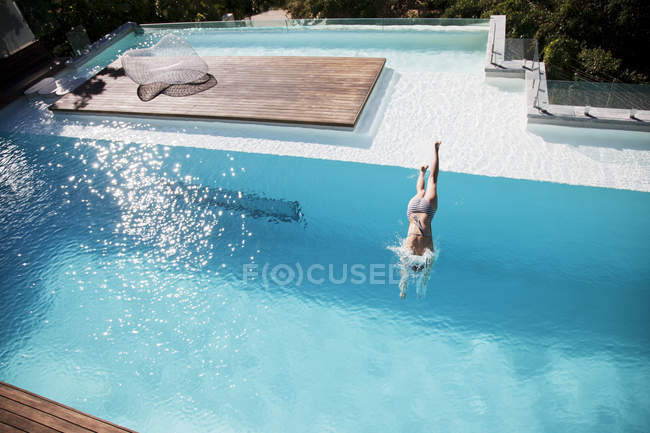Mulher mergulhando na piscina de luxo — Fotografia de Stock