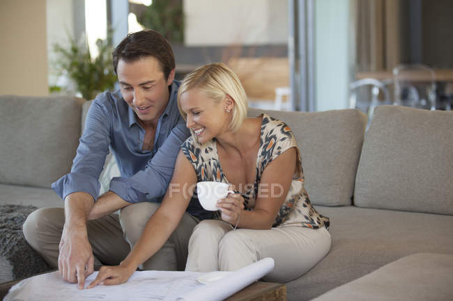 Couple examining blueprints on sofa — Stock Photo