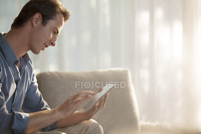 Людина використовує планшетний комп'ютер на дивані — стокове фото