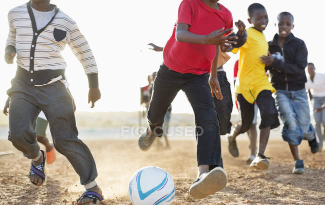 African boys playing soccer together in dirt field — Stock Photo
