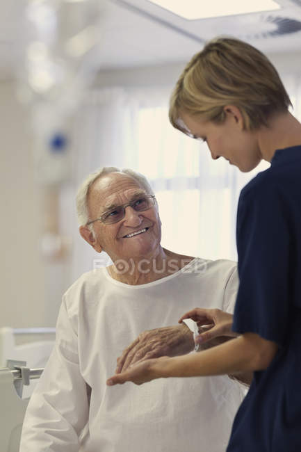 Enfermera leyendo pulsera médica paciente mayor en el hospital - foto de stock