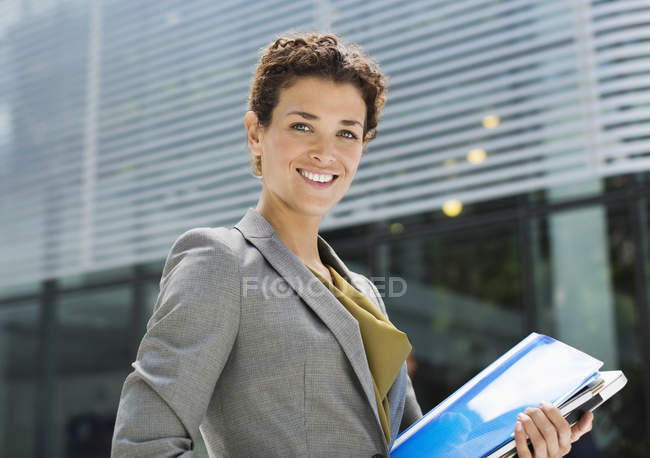 Feliz mujer de negocios llevando carpetas al aire libre - foto de stock