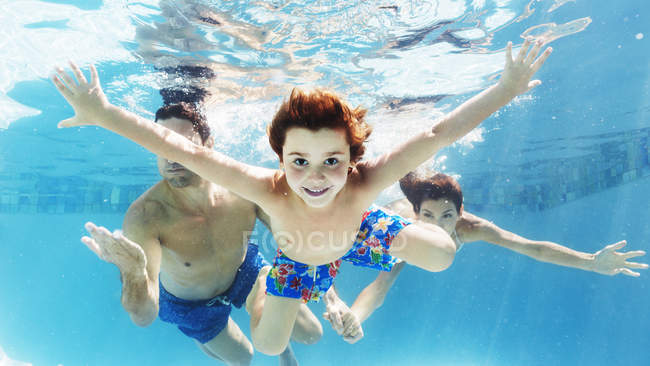 Familia nadando juntos bajo el agua en la piscina - foto de stock