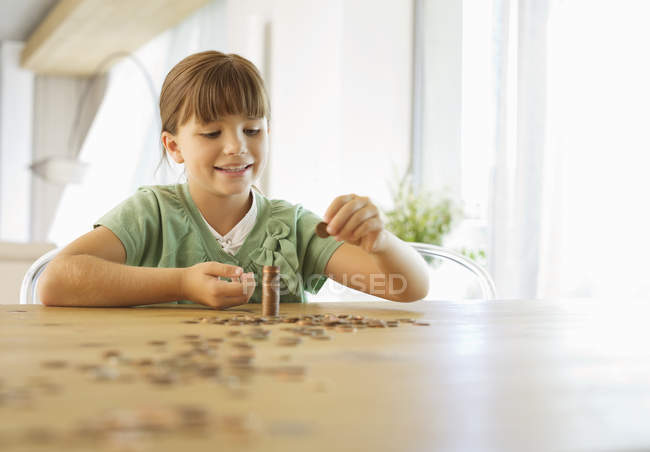 Girl stacking pennies on counter — Stock Photo