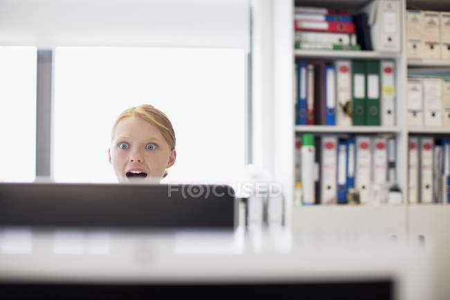 Здивована бізнес-леді читає пошту за комп'ютером в офісі — стокове фото
