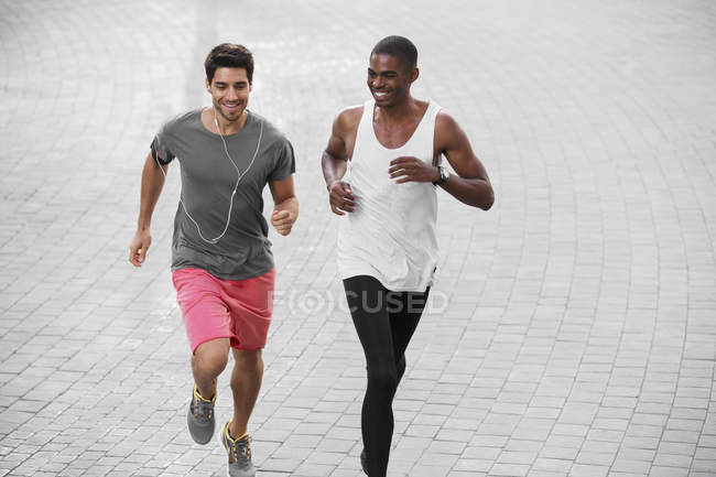Чоловіки бігають вулицями міста разом — стокове фото