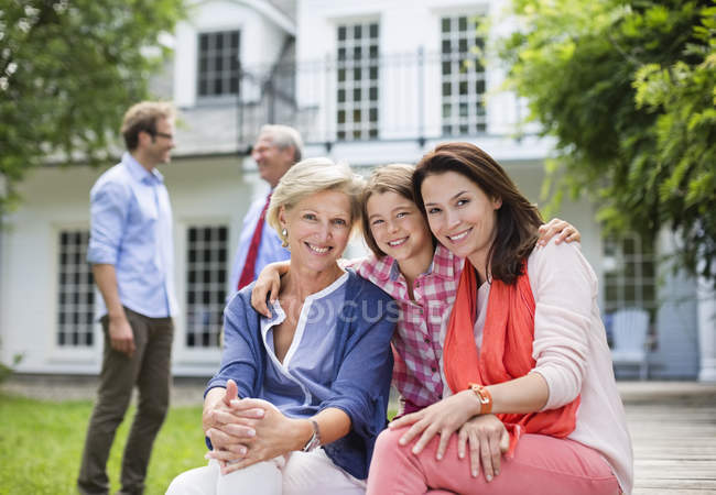 Familia sonriendo juntos fuera de casa - foto de stock
