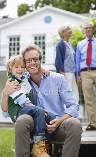 Padre e hijo sonriendo fuera de casa - foto de stock