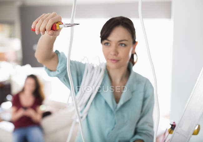 Skillful caucasian female electrician cutting wires in home — Stock Photo