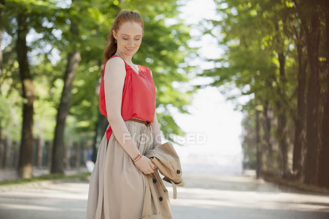 Lächelnde Frau blickt im Park nach unten — Stockfoto