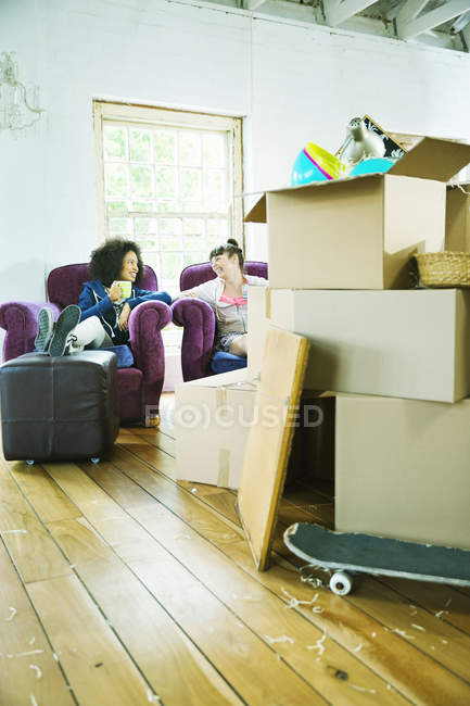 Jóvenes amigos relajarse en un nuevo hogar - foto de stock