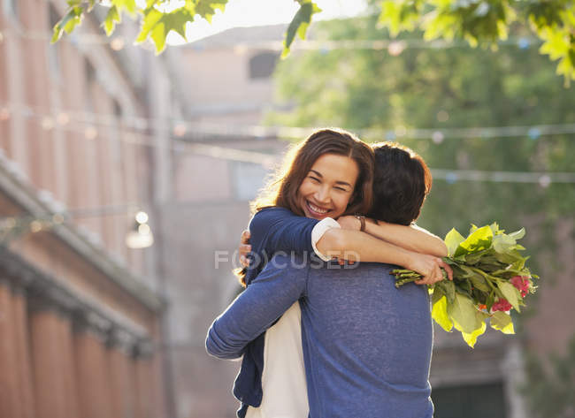 Усміхнена жінка з квітами обіймає чоловіка — стокове фото