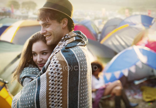Пара завернутых в одеяло снаружи палаток на музыкальном фестивале — стоковое фото