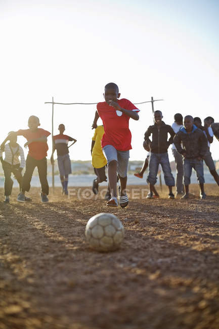 Chicos africanos jugando al fútbol juntos en el campo de tierra — Stock Photo